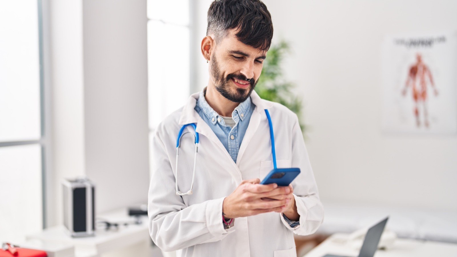 Médico de jaleco sorrindo enquanto confere no celular como o consultório aparece na busca